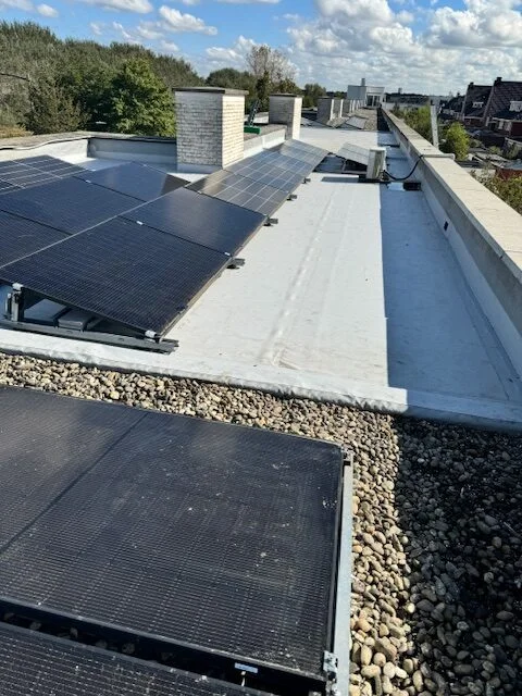 Zonnepanelen op een plat dak met grind en witte dakbedekking